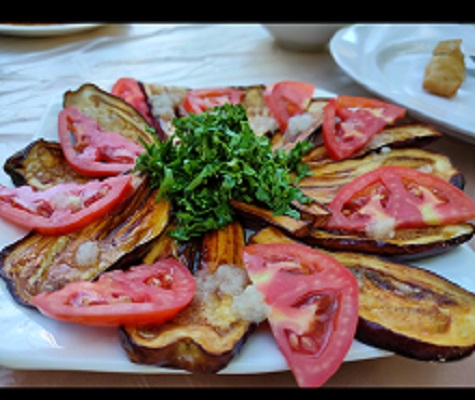 Fried eggplant with crushed garlic, tomato, and parsley