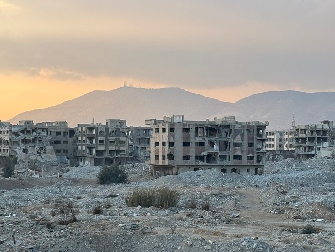 An image showing the devastation in Eastern Ghouta, with damaged buildings and empty streets representing the human tragedy and environmental damage caused by the Assad regime’s.